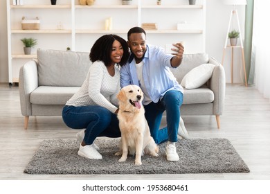 Happy Loving Family. Portrait Of Adult Black Couple Taking Selfie With Their Dog In Living Room, Sitting On The Floor At Home. Man Using Smartphone For Photo, Spending Time With Domestic Animal