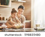 Happy loving family are preparing bakery together. Mother and child daughter girl are cooking cookies and having fun in the kitchen. Homemade food and little helper.