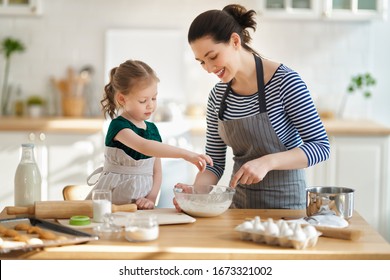 Happy Loving Family Are Preparing Bakery Together. Mother And Child Daughter Girl Are Cooking Cookies And Having Fun In The Kitchen. Homemade Food And Little Helper. 