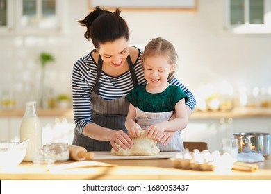 Happy Loving Family Are Preparing Bakery Together. Mother And Child Daughter Girl Are Cooking Cookies And Having Fun In The Kitchen. Homemade Food And Little Helper. 