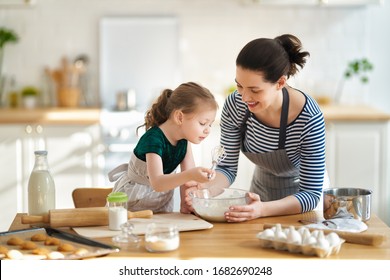 Happy Loving Family Are Preparing Bakery Together. Mother And Child Daughter Girl Are Cooking Cookies And Having Fun In The Kitchen. Homemade Food And Little Helper.                                