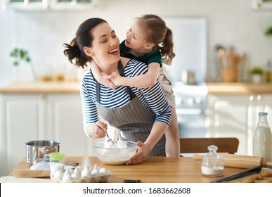 Happy loving family are preparing bakery together. Mother and child daughter girl are cooking cookies and having fun in the kitchen. Homemade food and little helper.                                 - Powered by Shutterstock