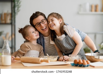 Eine glückliche Familie bereitet gemeinsam Bäckerei zu. Vater und Kinder Töchter Mädchen kochen Kekse und amüsieren sich in der Küche. Hausgemachtes Essen und wenig Helfer.  