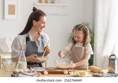 Happy loving family are preparing bakery together. Mother and child daughter girl are cooking cookies and having fun in the kitchen. Homemade food and little helper.  - Powered by Shutterstock