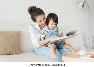 Happy Loving Family. Pretty Young Asian Mother Reading A Book To Her Daughter