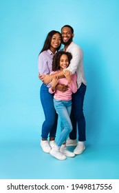 Happy Loving Family. Vertical Full Body Length Shot Of African American Woman And Man Embracing Smiling Girl Standing Isolated On Blue Studio Wall. Cheerful Mother And Father Posing With Daughter