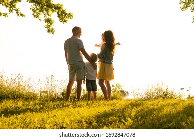 Happy Loving Family Walking Outdoor In The Light Of Sunset. Father, Mother, Son And Daughter.