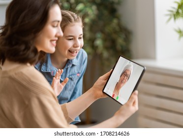 Happy Loving Family. Young Mother And Daughter Girl Using Tablet Pc For Remote Conversation With Grandma. Funny Mom And Lovely Child Are Having Fun Staying At Home.