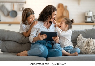 Happy loving family. Young mother and daughters girls using tablet pc for remote conversation with friends. Funny mom and lovely children are having fun staying at home.