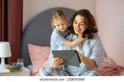 Happy Loving Family. Young Mother And Daughter Girl Using Tablet Pc. Funny Mom And Lovely Child Are Having Fun At Home.