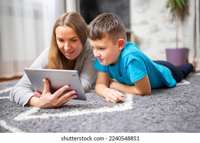 Happy loving family. Young mother and her son using tablet lying on carpet - Powered by Shutterstock