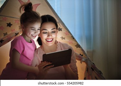 Happy Loving Family. Young Mother And Her Daughter Girl Play In Children Room At The Bedtime. Funny Mom And Lovely Child Are Having Fun With Tablet.