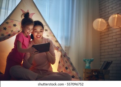 Happy Loving Family. Young Mother And Her Daughter Girl Play In Children Room At The Bedtime. Funny Mom And Lovely Child Are Having Fun With Tablet.