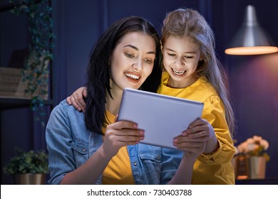 Happy Loving Family. Young Mother And Her Daughter Girl Are Playing In Bedroom. Funny Mom And Lovely Child Are Having Fun With Tablet.