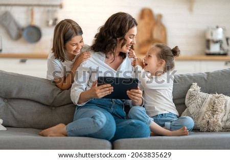 Happy loving family. Young mother and daughters girls using tablet pc for remote conversation with friends. Funny mom and lovely children are having fun staying at home.