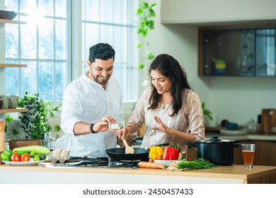 Happy loving Indian asian young couple cooking food in kitchen together, hugging, standing at table - Powered by Shutterstock