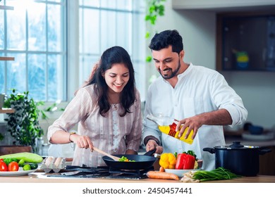 Happy loving Indian asian young couple cooking food in kitchen together, hugging, standing at table - Powered by Shutterstock