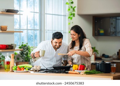 Happy loving Indian asian young couple cooking food in kitchen together, hugging, standing at table - Powered by Shutterstock