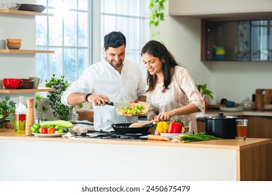 Happy loving Indian asian young couple cooking food in kitchen together, hugging, standing at table - Powered by Shutterstock