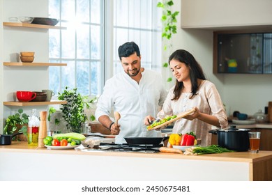 Happy loving Indian asian young couple cooking food in kitchen together, hugging, standing at table - Powered by Shutterstock