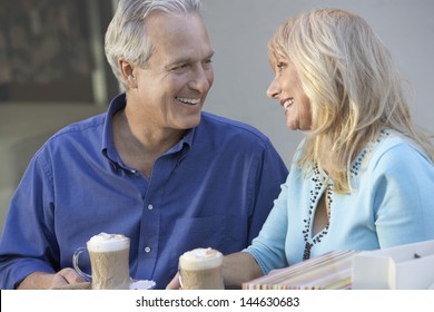 Happy And Loving Middle Aged Couple Sitting At Caf_ While On Shopping Trip