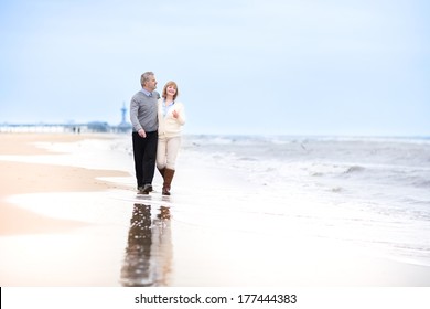 Happy Loving Middle Aged Couple Walking On A Beautiful Beach In Holland