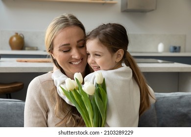 Happy Loving Mom Hugging Cute Little Daughter Kid With Gratitude, Love, Tenderness, Holding Bunch Of Flowers. Sweet Child Giving Tulips To Mommy Due To Mothers Day, Birthday, 8 March