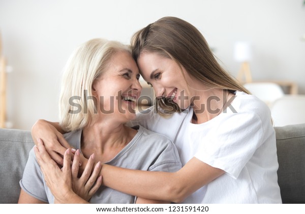 Happy\
loving older mature mother and grown millennial daughter laughing\
embracing, caring smiling young woman embracing happy senior middle\
aged mom having fun at home spending time\
together
