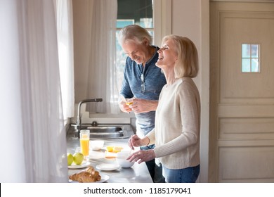 Happy loving senior couple having fun preparing healthy food on breakfast in the kitchen, mature smiling man and woman laughing cooking together on weekend morning, aged old family at home concept - Powered by Shutterstock