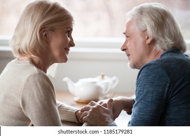 Happy loving senior middle aged retired family couple holding hands looking in the eyes giving care psychological support to older, understanding in good relations, trust devotion in marriage concept - Powered by Shutterstock