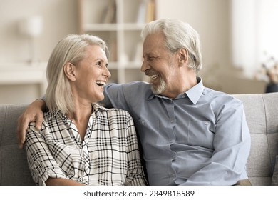 Happy loving senior retired husband and wife hugging with warmth, affection, sitting close on home sofa, talking, chatting, laughing, enjoying marriage, relationship, friendship - Powered by Shutterstock