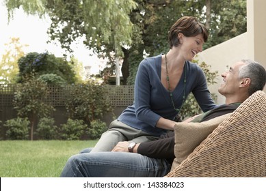 Happy Loving Woman Sitting On Man's Lap In Lawn