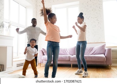 Happy Loving Young African American Family Dancing To Favorite Song At Home. Smiling Dad And Mom Teaching Young Girl And Boy Modern Style. Having Fun Together With Two Cute Little Kids In Living Room