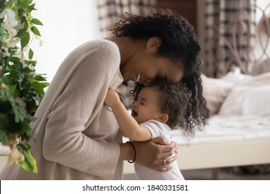 Happy Loving Young African American Mother Hug Embrace Paly With Little Cute Ethnic Baby Infant At Home. Smiling Caring Biracial Mom Feel Playful Enjoy Tender Family Moment With Small Toddler Child.