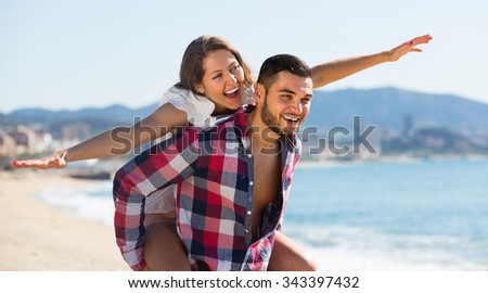 Happy loving young couple having fun at sandy beach
