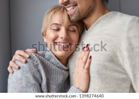 Happy loyal woman with closed eyes leaning on chest of reliable man while spending time at home