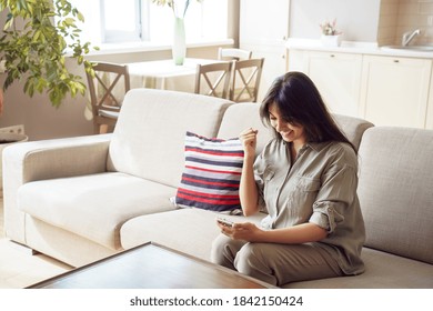Happy lucky indian woman winner holding smartphone reading message celebrating mobile victory, triumph, success, getting prize free discount voucher online in app, using cellphone sit on sofa at home. - Shutterstock ID 1842150424