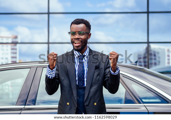 happy lucky and successful afro american
businessman rejoices and enjoying success ahead of the car. concept
of a good deal and
victory