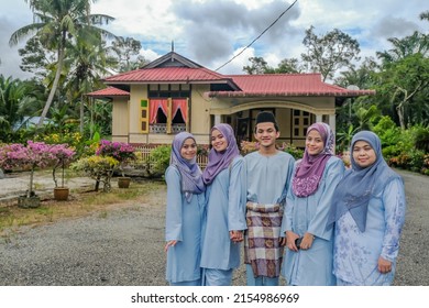   Happy Malay Family In Traditional Clothing And Traditional Malay House During Hari Raya. Malaysian Family Lifestyle At Home. Happiness Concept.