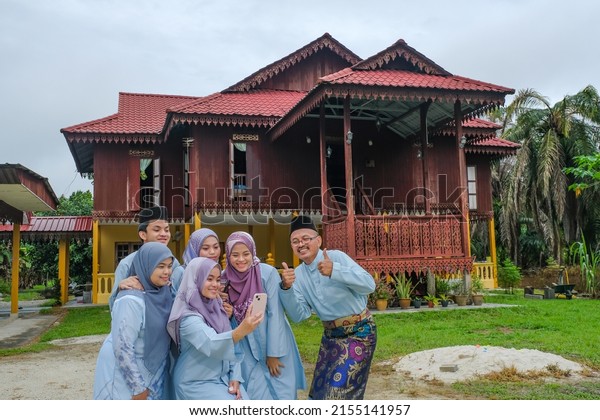 Happy Malay family in traditional clothing and\
traditional Malay house during Hari Raya. Malaysian family\
lifestyle at home. Happiness\
concept.