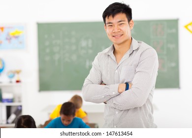 happy male asian elementary school teacher in classroom