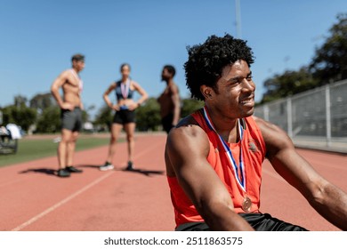 Happy male athlete with gold medal relaxing by the track  - Powered by Shutterstock