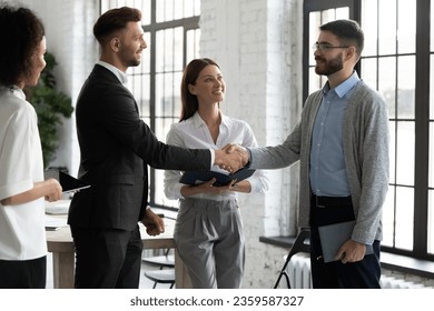 Happy male business partners shake hands get acquainted greeting in office, smiling businessmen handshake close deal or make agreement after successful negotiation, partnership concept - Shutterstock ID 2359587327