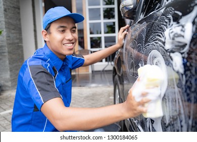 Happy Male Car Cleaning Service Worker Washing A Black Car