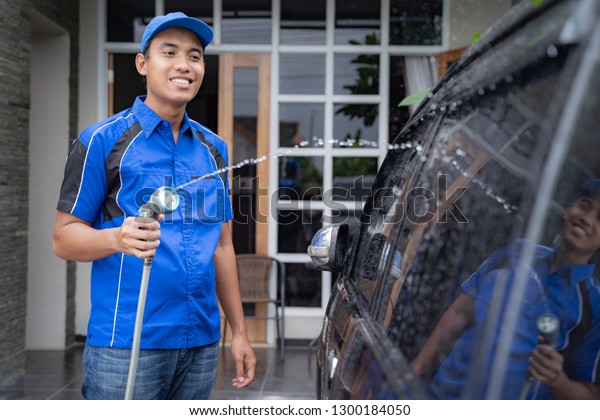 happy male car cleaning service worker washing a\
black car