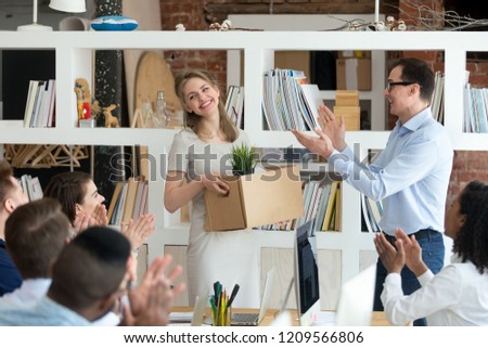 Happy male CEO and company workers applaud welcoming excited new female employee to team, smiling boss and colleagues clap acquainted with newcomer holding box at corporate meeting. Employment concept
