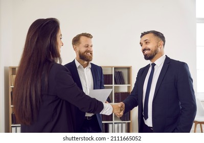Happy male client exchanges a handshake with a female lawyer, business adviser or financial consultant. Businessman in a suit smiling and shaking hands with a woman, thanking her for professional help - Shutterstock ID 2111665052