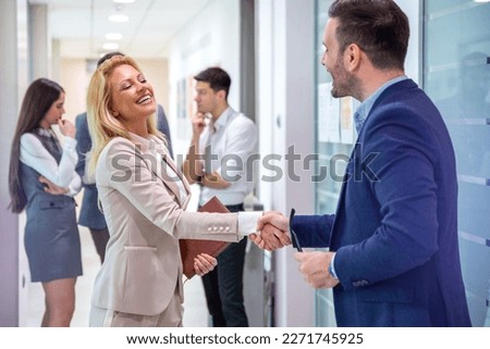 Happy male company director, delighted to meet his new female colleague, greeting attractive blond haired lady to his business team. Handshake and new employee concept.