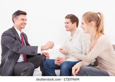 Happy Male Consultant Giving Visiting Card To Young Couple
