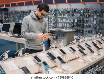 Happy Male Customer Choosing Smartphone In The Mobile Phone Shop. Difficult Decision. Various Choice. He Is Smiling